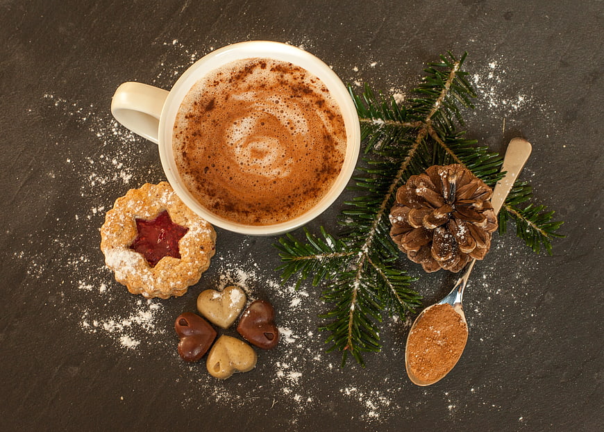 Flat lay of hot chocolate, Christmas cookies, and pine branch on dark background