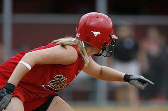Female softball player in red uniform and helmet