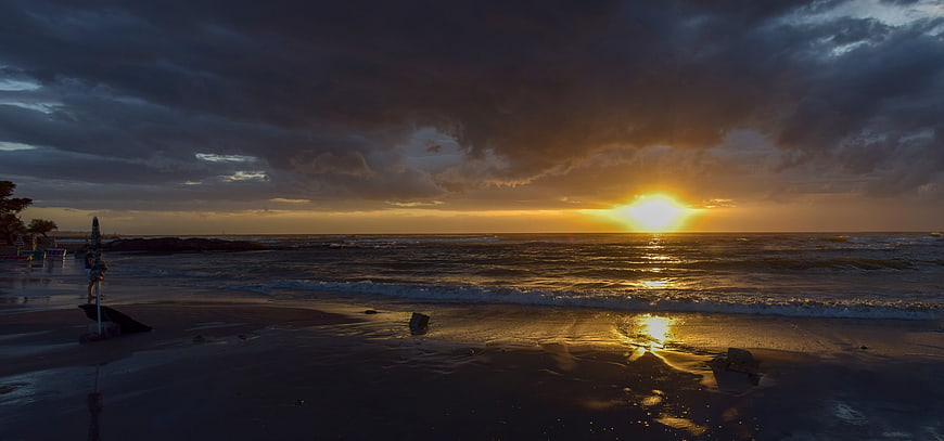 Dramatic Sunset Over Ocean With Golden Light And Clouds