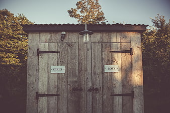Rustic wooden outdoor toilet with girls and boys signs