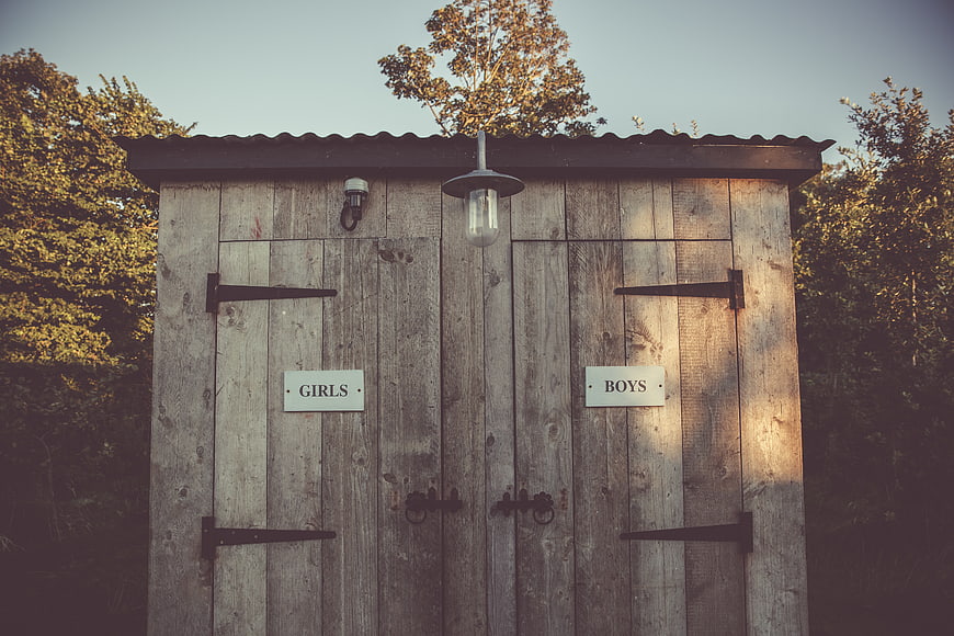 Rustic wooden outdoor toilet with girls and boys signs