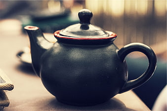 Close-up of a black ceramic teapot with red rim