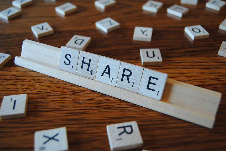 Scrabble tiles spelling SHARE on wooden table