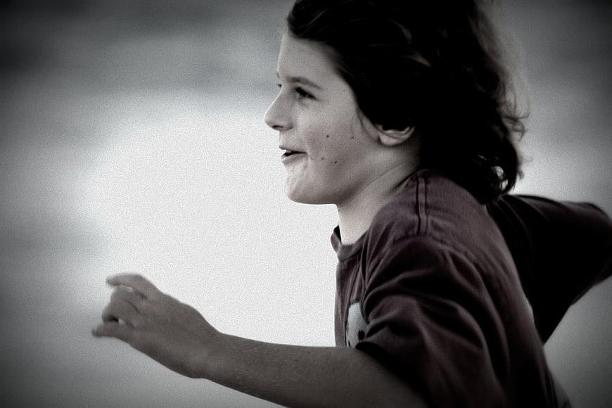 Profile of a smiling boy running outdoors in black and white