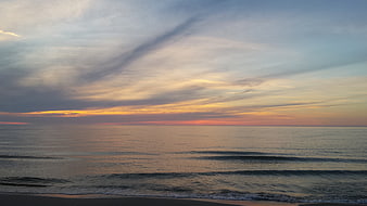 Serene Sunset Over Calm Ocean Waves on Sandy Beach