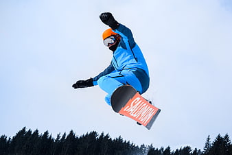 Snowboarder performing high jump against blue sky