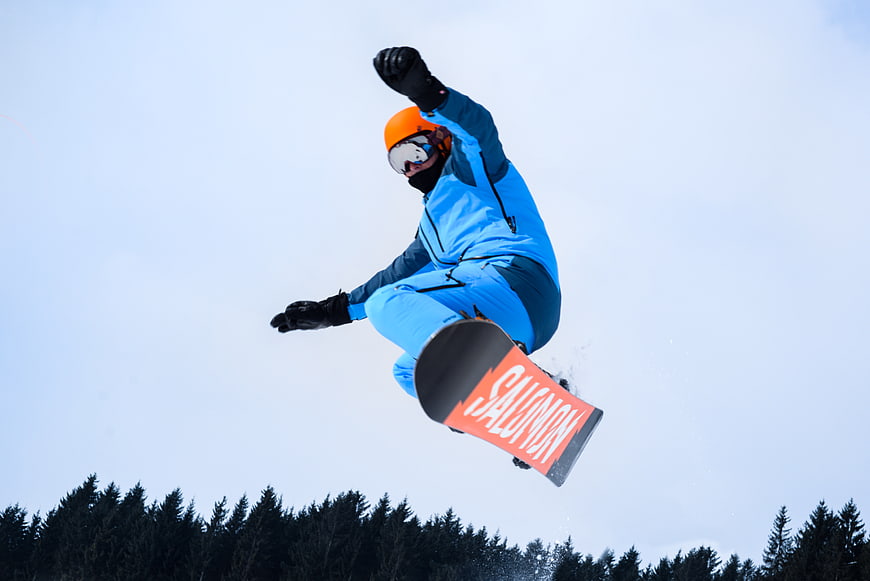 Snowboarder performing high jump against blue sky