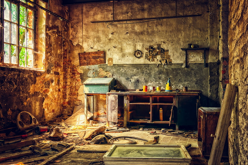 Abandoned workshop interior with peeling walls and workbench