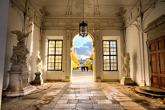 Baroque Palace Hallway with Statues and Autumn Garden View