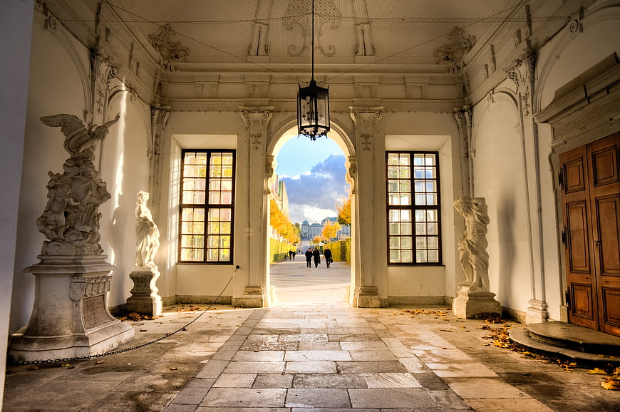Baroque Palace Hallway with Statues and Autumn Garden View
