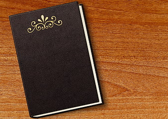 Black leather book with gold emblem on wooden table