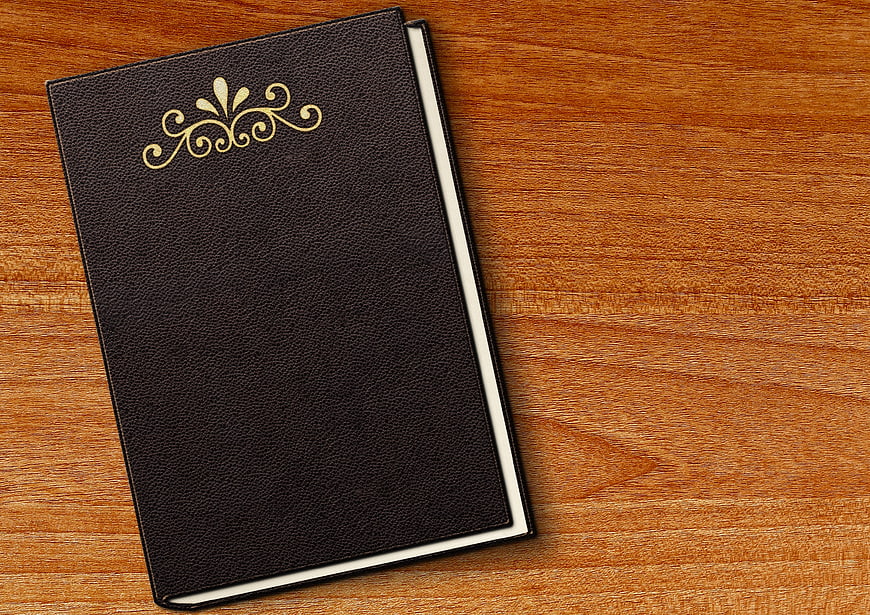Black leather book with gold emblem on wooden table