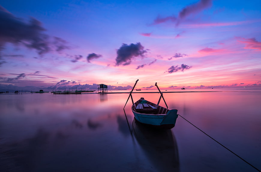 Long Exposure Sunset Reflection on Calm Tropical Beach with Boat
