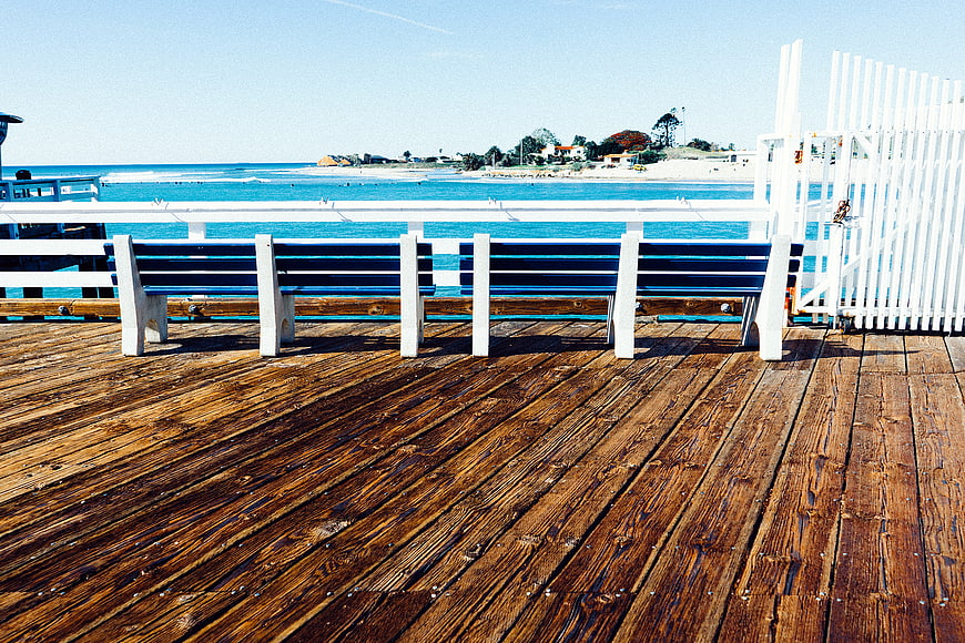 Wooden Pier with White Bench Overlooking Blue Ocean