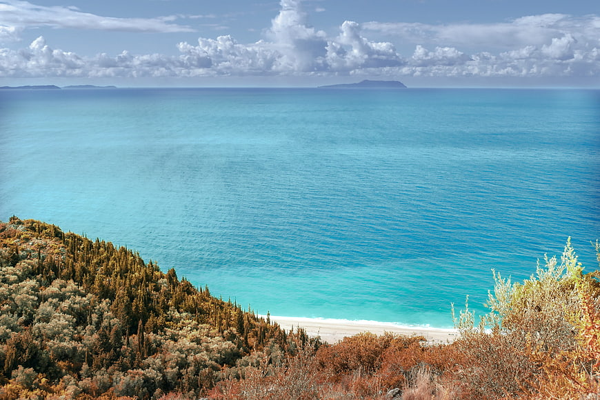 Coastal landscape with turquoise sea, white sand beach, and green vegetation