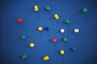 Colorful push pins scattered on blue bulletin board background