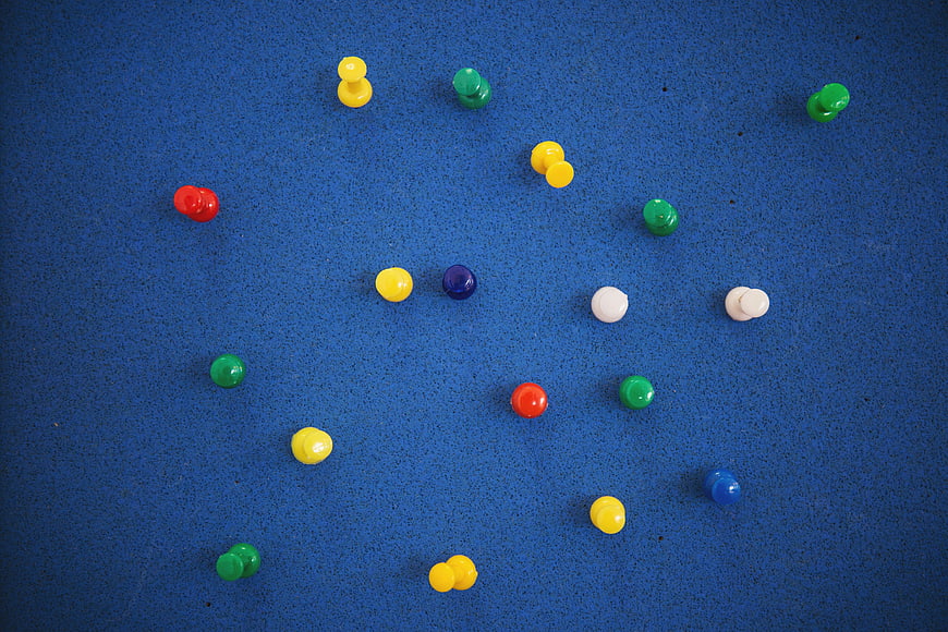 Colorful push pins scattered on blue bulletin board background