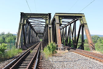 Rusty steel railway bridge with tracks leading into distance