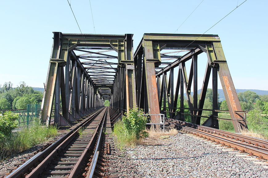 Rusty steel railway bridge with tracks leading into distance