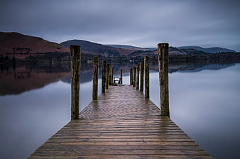 Wooden pier extending into calm lake with mountain reflections