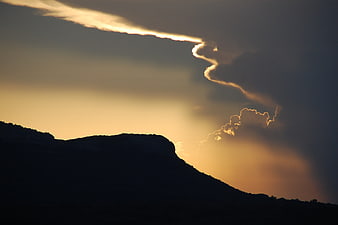 Dramatic sunset silhouette of mountain with unique cloud formation
