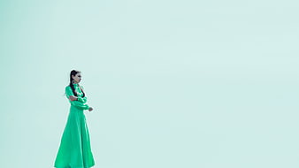 Young woman in green dress standing in vast white landscape