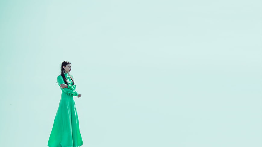 Young woman in green dress standing in vast white landscape
