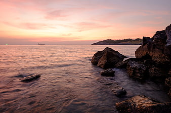 Serene Sunset Seascape with Rocky Shoreline and Silky Water