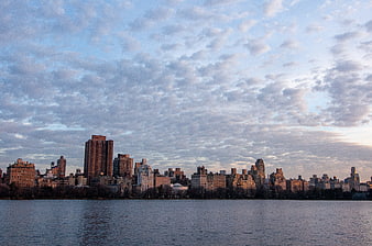 Manhattan skyline at dusk with clouds over water