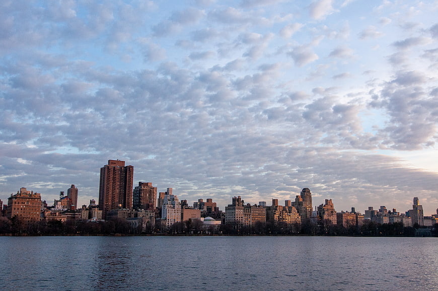 Manhattan skyline at dusk with clouds over water