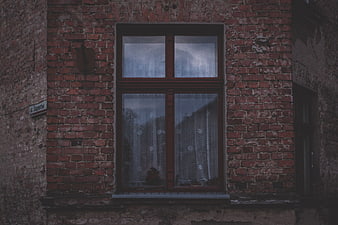 Vintage red brick window with lace curtains on old building