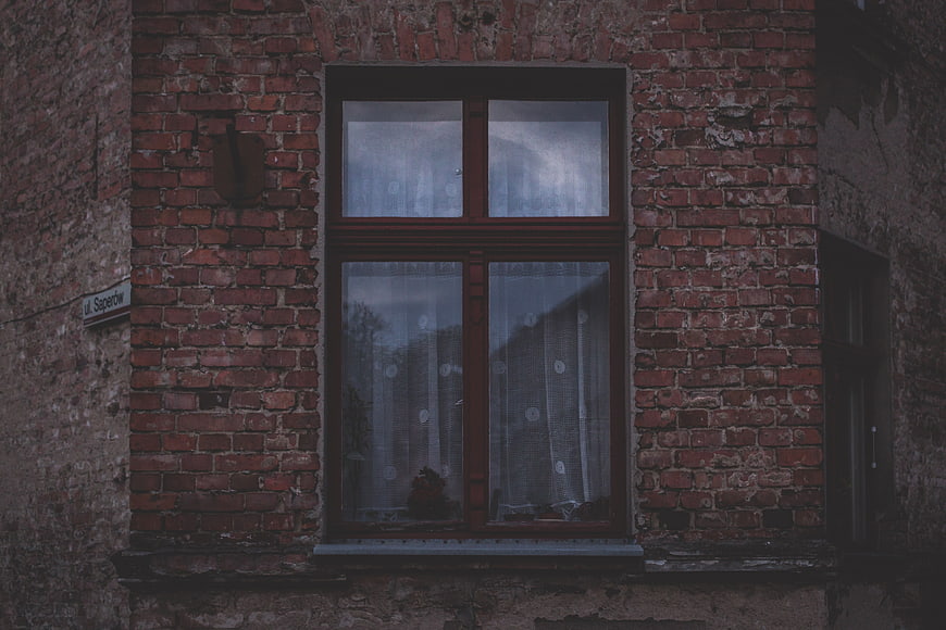 Vintage red brick window with lace curtains on old building