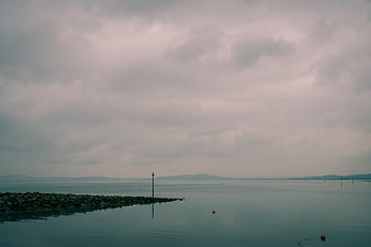Moody Seascape with Rocky Jetty Under Overcast Sky