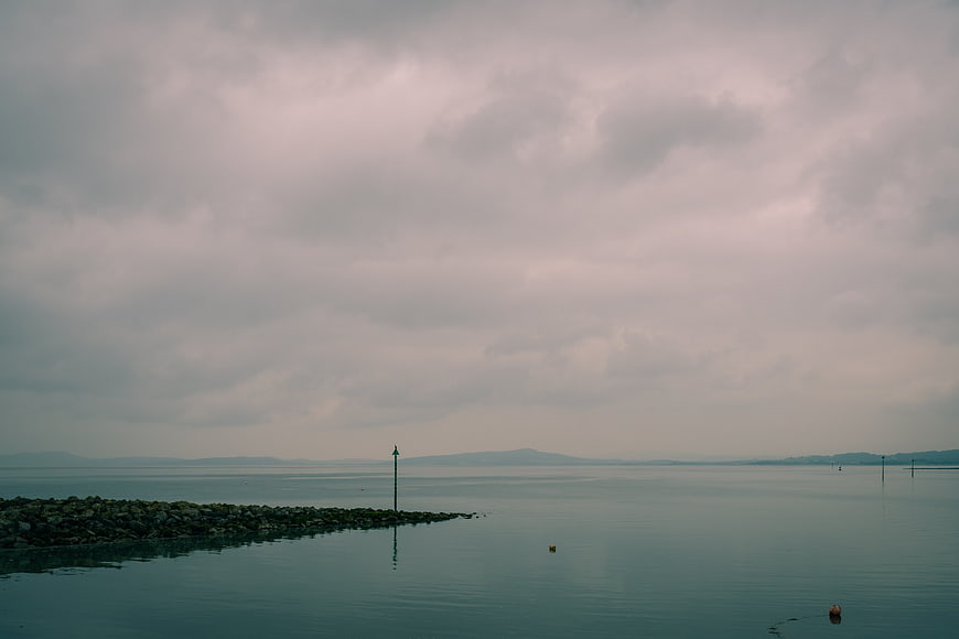 Moody Seascape with Rocky Jetty Under Overcast Sky