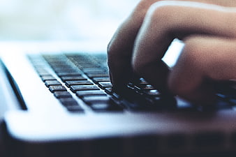 Close-up of hands typing on a laptop keyboard with shallow depth of field