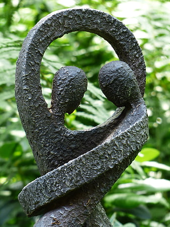 Abstract metal sculpture of two figures embracing in a garden