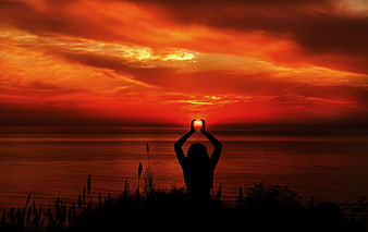 Silhouette of Woman Holding Sun Over Ocean at Sunset