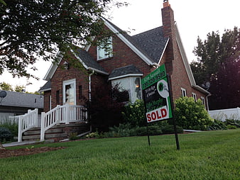 Brick House with Sold Real Estate Sign in Front Yard