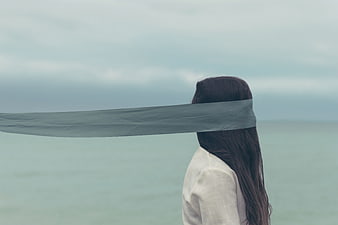 Woman with blindfold standing by the ocean