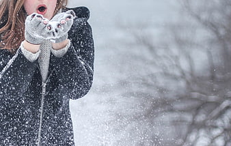 Woman Blowing Snowflakes from Gloves in Winter