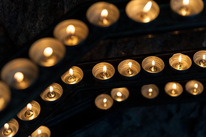 Rows of lit tealight candles in a dark setting