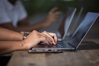 Close-up of hands typing on laptop in office workspace