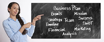 Businesswoman pointing to business plan keywords on a blackboard