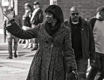 Black and white photo of woman waving in winter coat