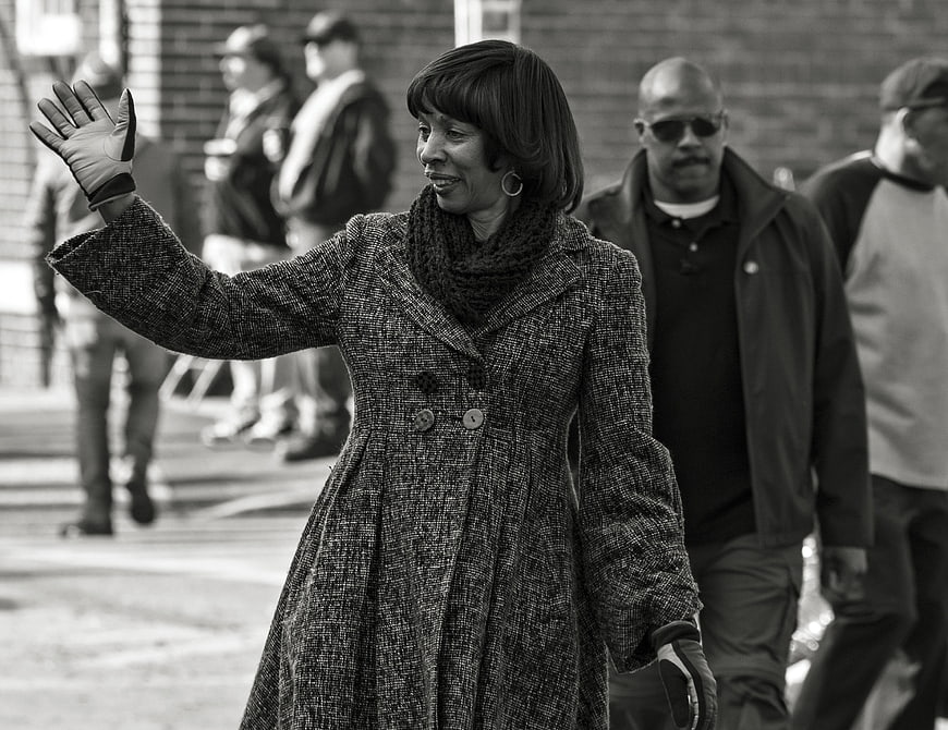 Black and white photo of woman waving in winter coat
