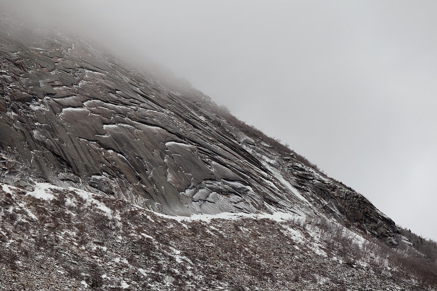 Foggy Rocky Mountain Slope with Snow Patches