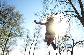 Girl Jumping Silhouette Against Sun and Trees