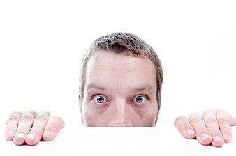 Scared man peeking over white board with hands