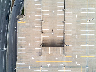 Aerial view of lone person walking in empty parking lot