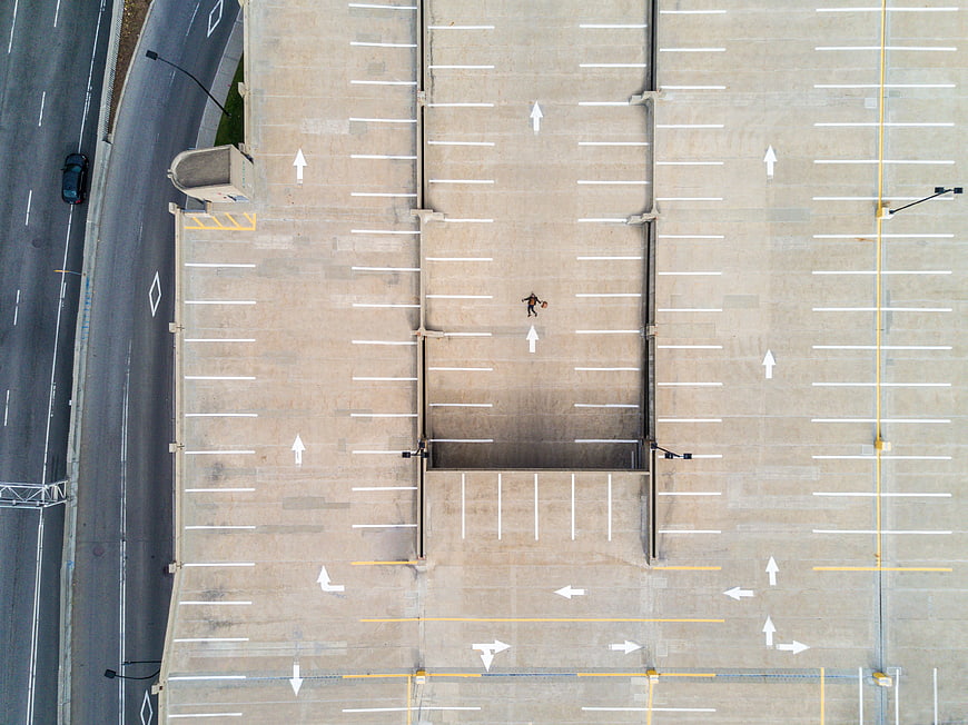 Aerial view of lone person walking in empty parking lot